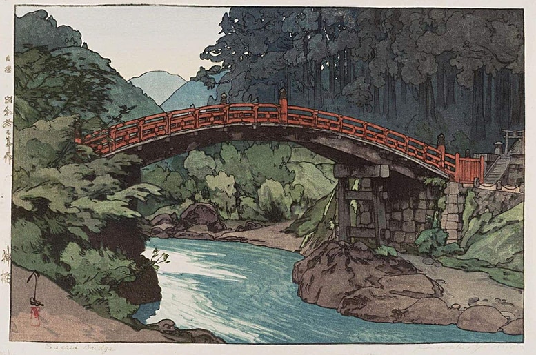 Sacret bridge by Yoshida Hiroshi An image of the woodblock print of Sacred bridge by Yoshida Hiroshi showing a wooden arched bridge with red wooden railings crossing over a gently flowing blue stream with green forests on both sides and hills visible in the distance.