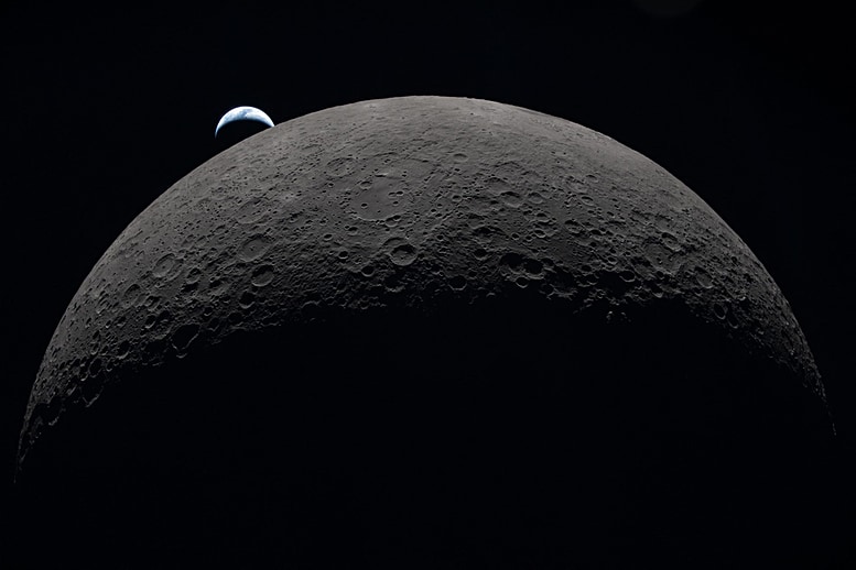 A New View of the Moon A view of the dark side of the moon. Only the top half of it can be seen, dark gray in color, floating in the blackness of space. Floating beyond it, just above the top left portion of the moon, is a crescent of a tiny blue-white marble, our Earth, just as it is about to set behind the moon.